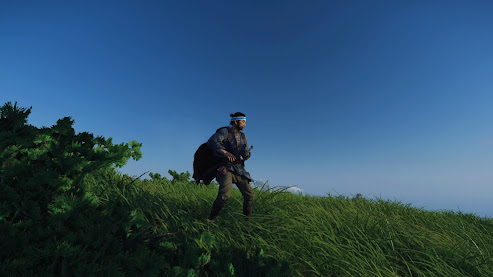 Ghost of Tsushima screenshot - Jin on top of a grassy hill with a big blue sky of the morning behind him. He is robed in blue with a sky blue headband.