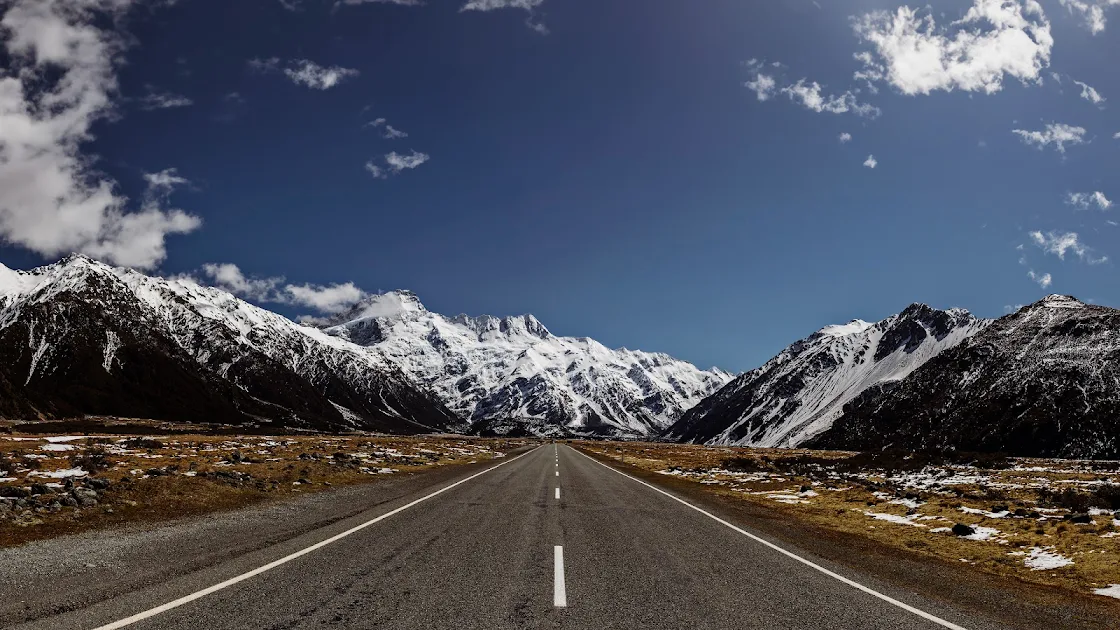 High-definition 4K wallpaper of a straight road leading towards snow-covered mountains under a clear blue sky. toplist wallpaper