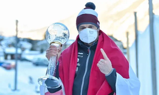 Martin Durkus segura o troféu da copa do mundo. Nas suas costas está uma bandeira da Letonia