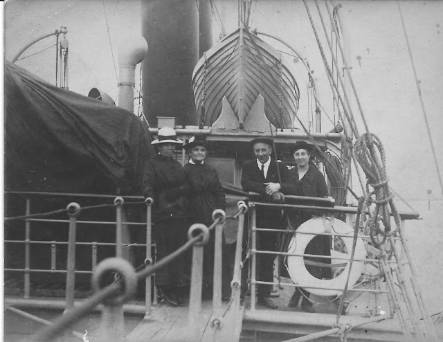 4 people standing on the upper deck of a steamboat