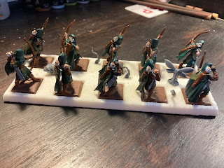 Ten cloaked archers standing in a line, five by two, on top of a white plastic tray.