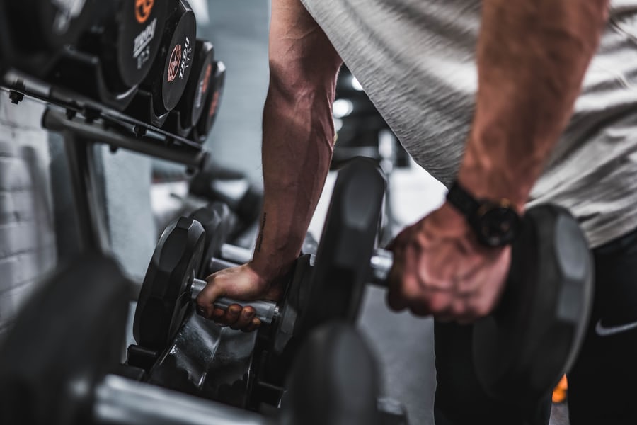 Two muscled hands about to lift weights to lose weight