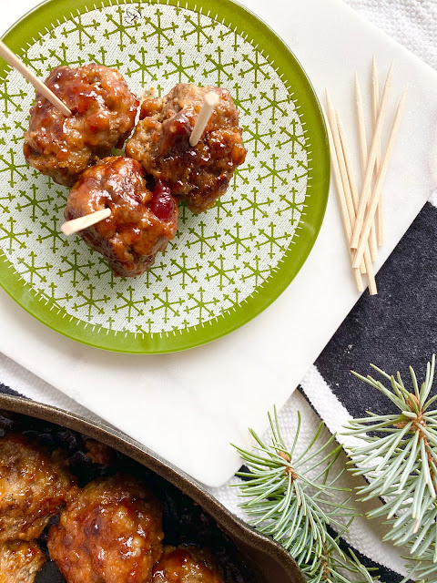 Plated meatballs with toothpicks next to a skillet