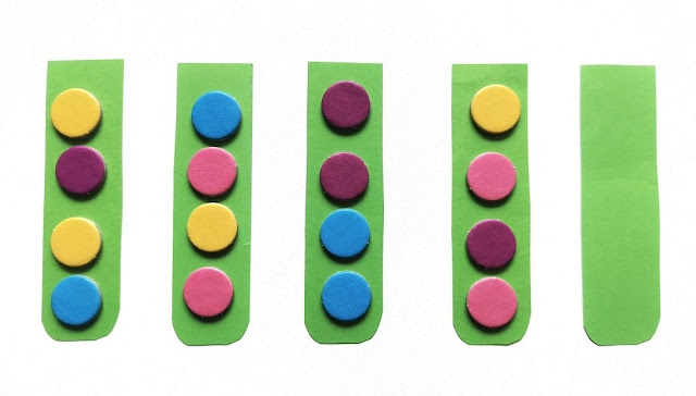 pięć zielonych probówek a w nich kulki w pięciu kolorach, rozłożone w przypadkowej kolejności w probówkach