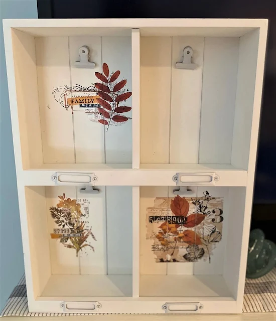 Photo of a white shadowbox with fall decor transfers in the back.