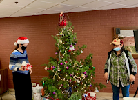 Jen and Amanda beside the tree passing out secret Santa gifts at Colorado Center For The Blind.