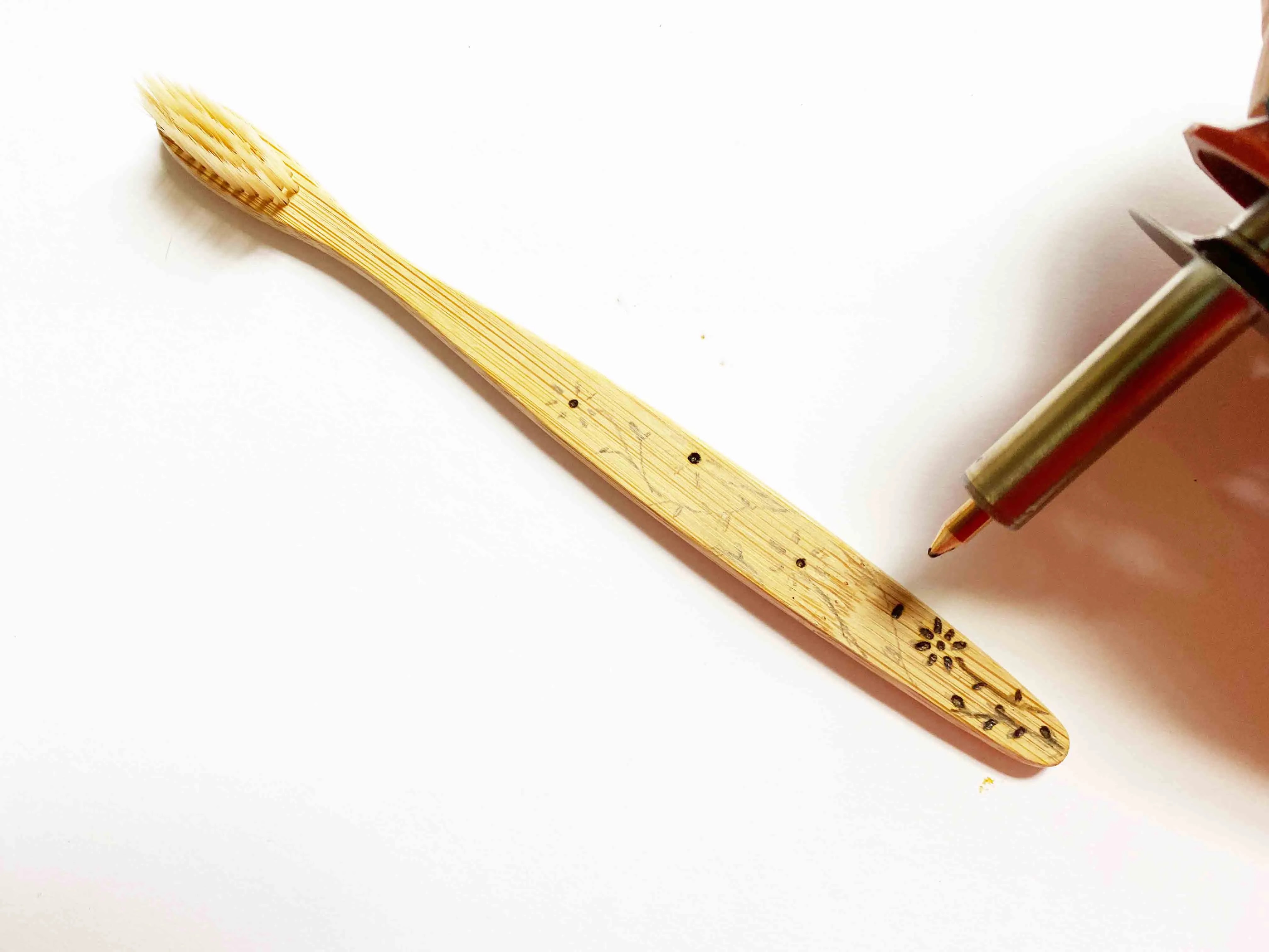 Outil de gravure sur bois gravant un motif floral sur une brosse à dents en bambou
