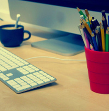 Un clavier, un porte-stylo et une tasse de thé sur une table de bureau