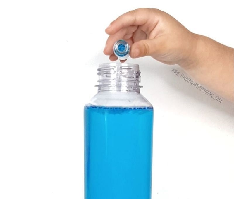 adding glitter to sensory bottle