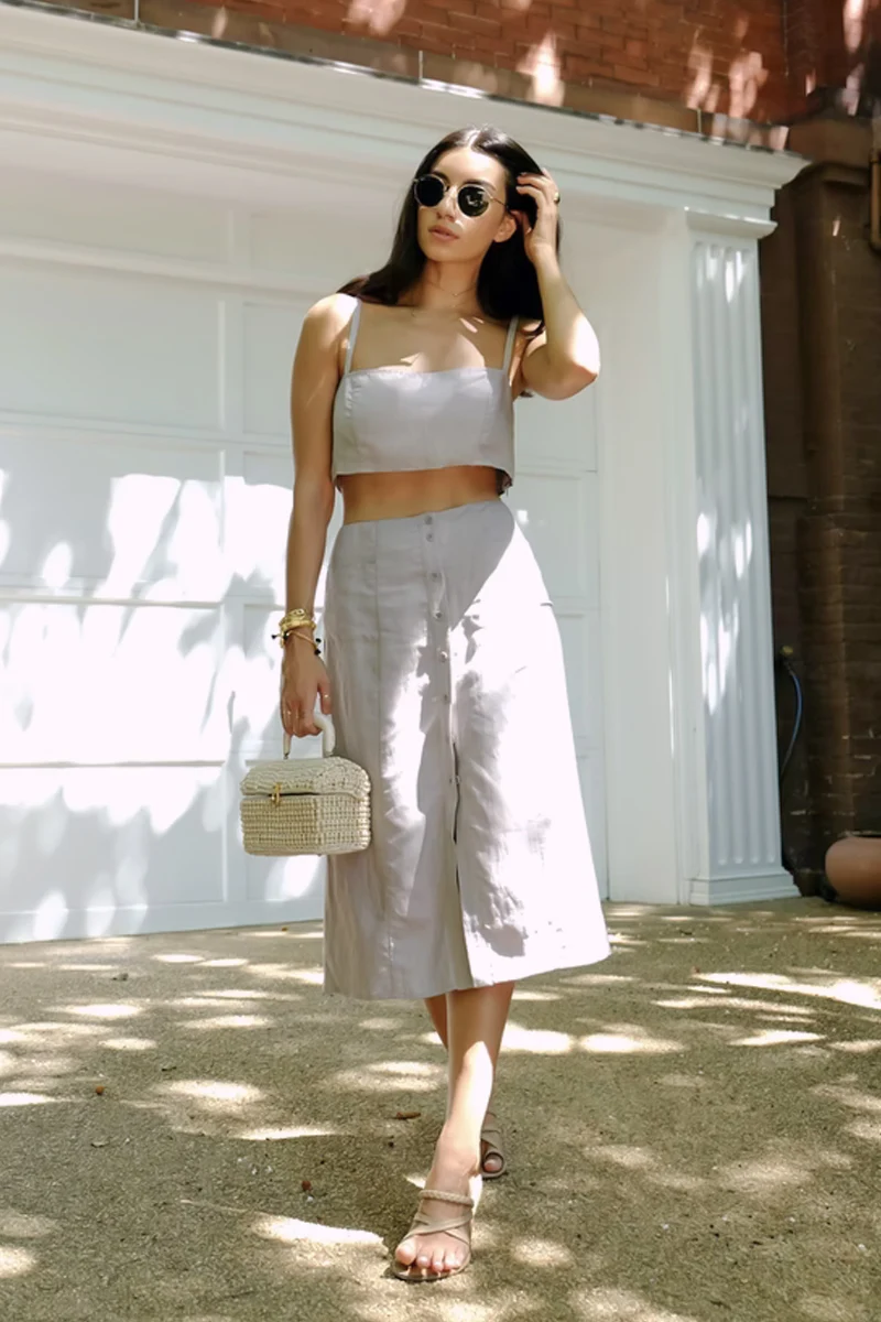 woman in a stylish two-piece suit is posing on the street