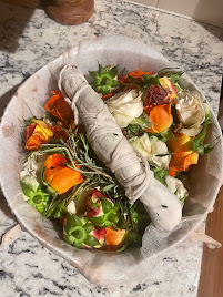 Bowl lined with cheescloth filled with orange, white and pink roses and a wand made of rosemary springs