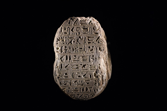 Clique na Ficção - Um fundo preto com uma pedra cheia de escritas cuneiformes no meio