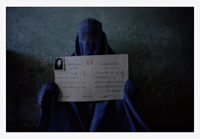 An Afghan Woman in blue burqa holds fer Diploma, Kabul, Afghanistan, 1998