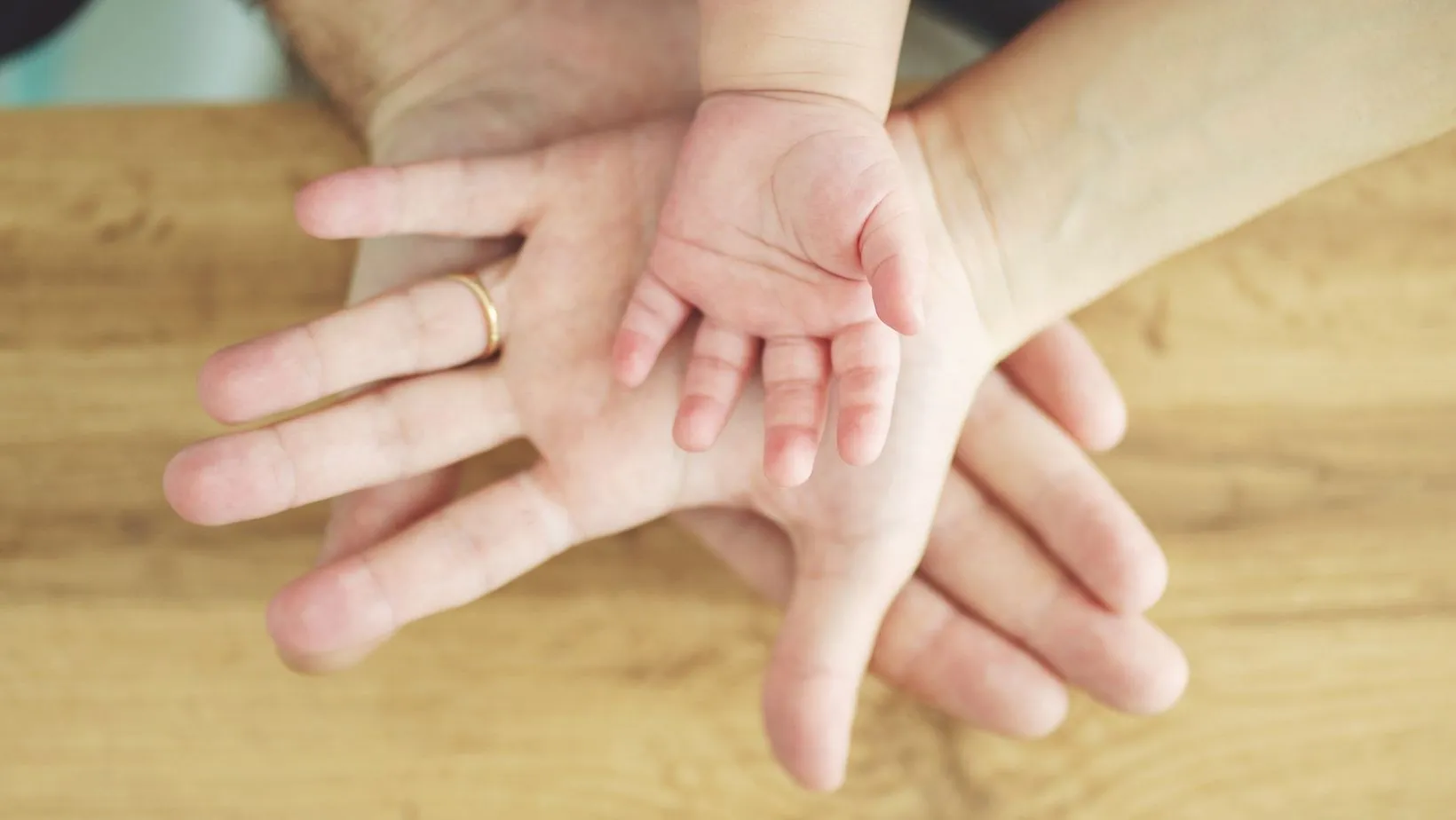 canva stock image of hands of two parents and a baby