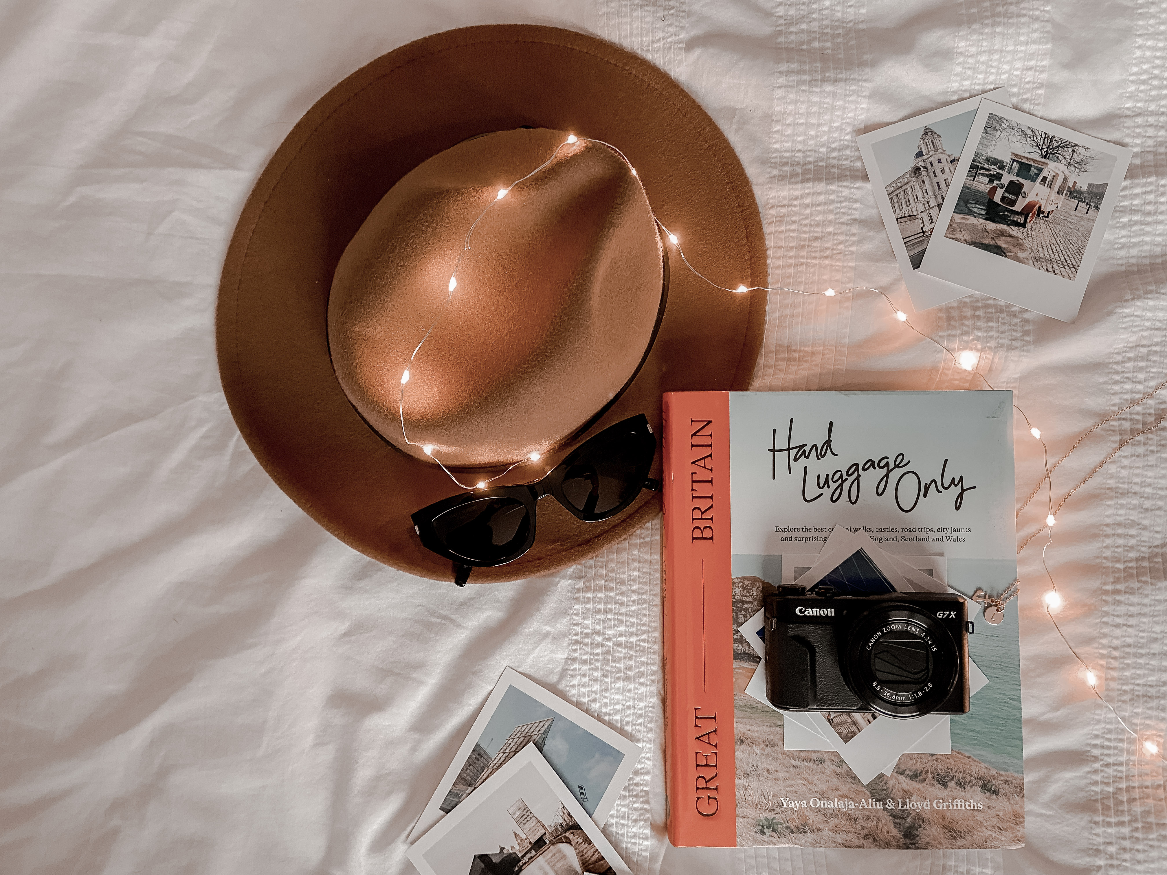 A flatlay of a brown fedora hat and travel book.