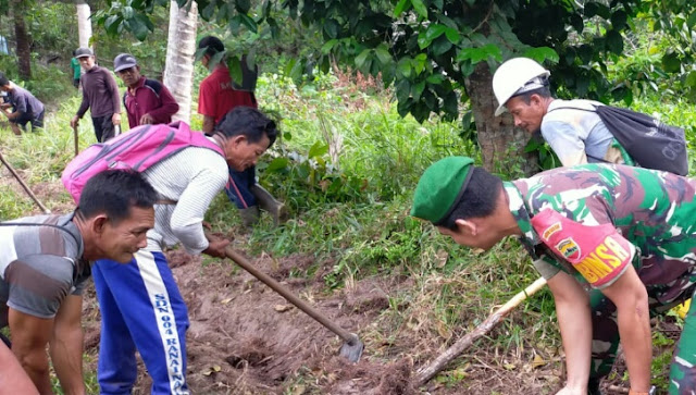 Babinsa Desa Kelanga Ikut Membantu Warga Memindahkan Pipa Paralon Saluran Air