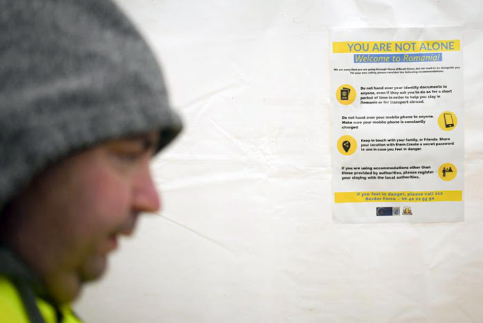 A volunteer walks past a poster giving advice on personal safety at the Romanian-Ukrainian border, in Siret, Romania, Monday, March 7, 2022. Concerns are developing about how to safeguard the most vulnerable migrants from being targeted by human traffickers or becoming victims of other sorts of exploitation as millions of women and children escape over Ukraine's borders in response to Russian aggression. Image Credit : (AP Photo/Andreea Alexandru)