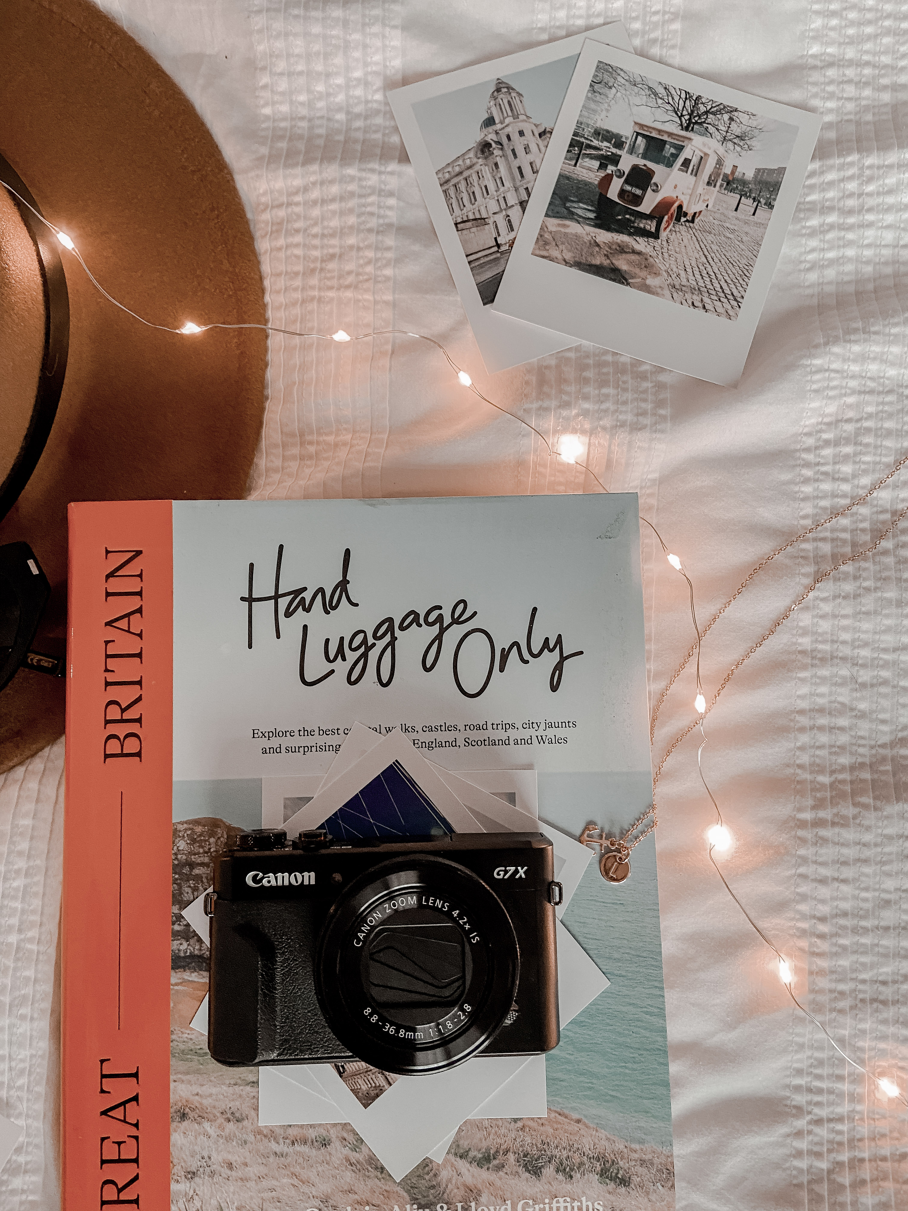 A flatlay of a brown fedora hat and travel book.