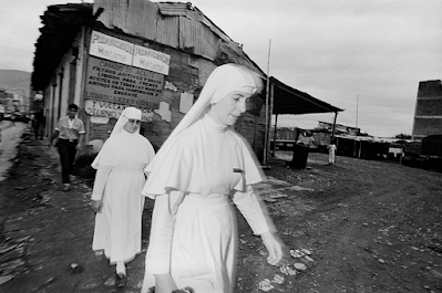 black and white photograph of 2 women in white head coverings and white dresses leaving a building in Armenia, Columbia