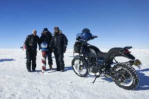 Expedition team with the Royal Enfield Himalayan at the geographic South Pole, Antarctica