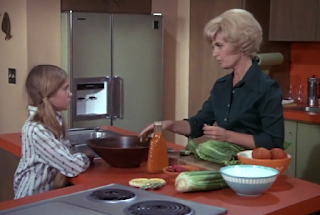 Carol and Marcia talk in the kitchen.