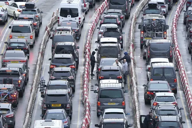 People stand by their cars as traffic is jammed at the Port of Dover as the Easter getaway begins, in Kent, England, Saturday April 1, 2023. The Port of Dover declared a critical incident as high levels of traffic caused coach passengers to experience lengthy delays. (Gareth Fuller/PA via AP)