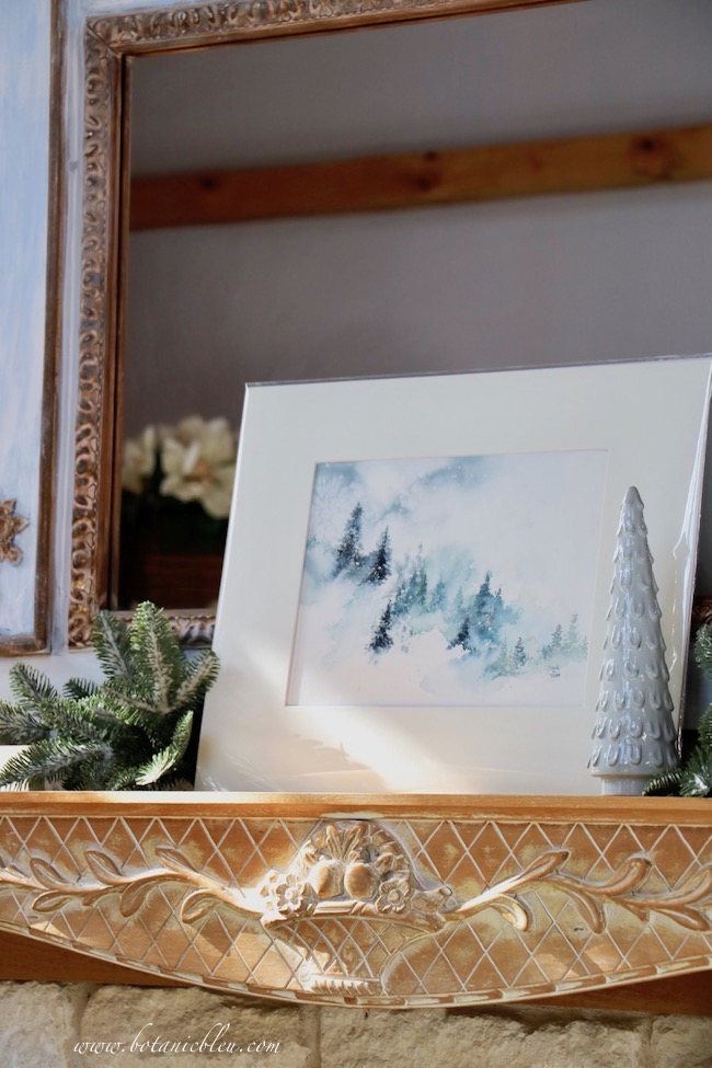 A watercolor of snowy evergreen woods will transition from Christmas decor to late Winter decor