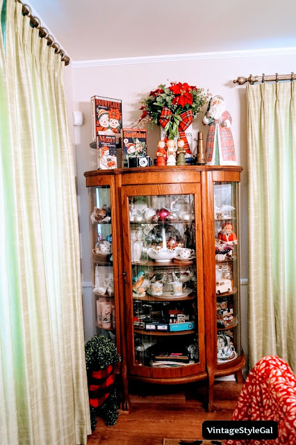 China cabinet decorated for Christmas and red poinsettias in milk cooler