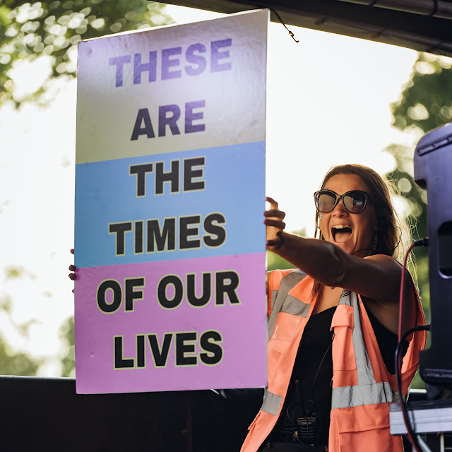 Rachel, one of the Yonder Events organisers, holding up a sign that says 'These are the times of our lives' on stage