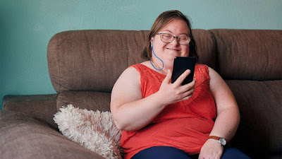 Woman with Down's Syndrome looking at her cellphone and smiling photo
