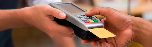 pessoa pagando com o cartão de crédito em uma maquinha de cartão