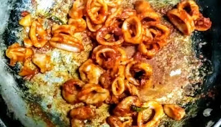 Cooking squid fry on tawa till become dry and coated with masala