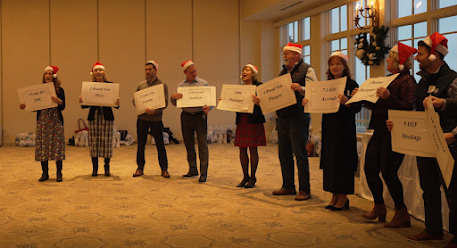 Managers wearing Santa hats singing and holding posters with song lyrics