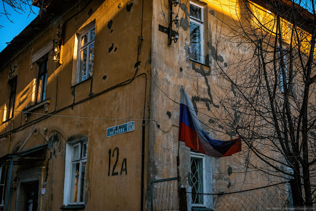 Российский потрепанный флаг на фоне обшарпанного здания