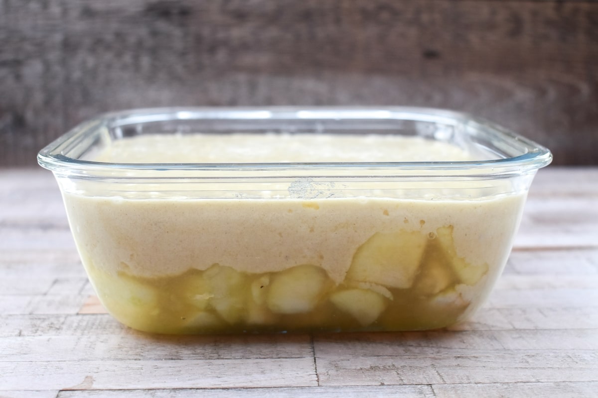 cake batter over stewed apples in a glass casserole dish