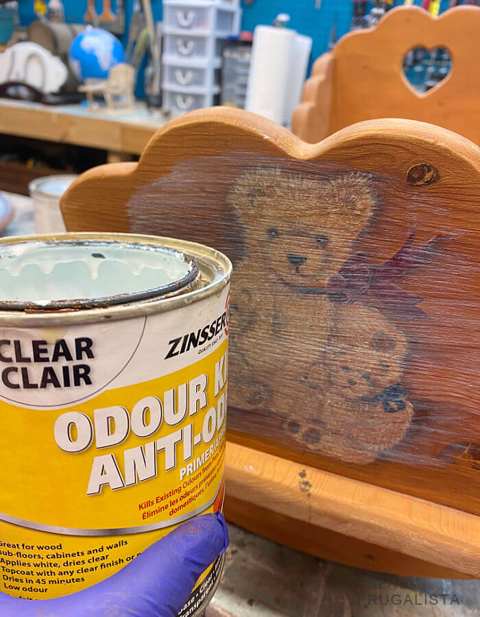 Brushing clear primer over a graphic on a wooden doll cradle makeover.