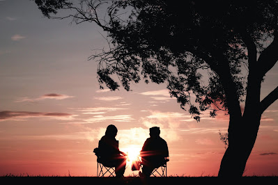 Two people sitting in front of a sunset talking (Credit: Harli Marten/Unsplash)