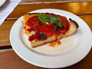 A slice of Detroit-style pizza with a thick base..