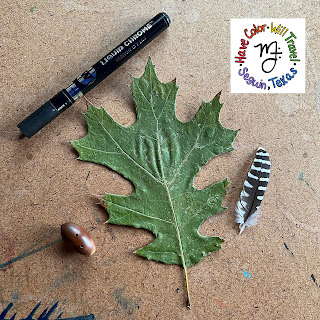 A pressed maple leaf lying on a table surrounded by a pumpmarker, an owl leaf, and a shiny acorn.