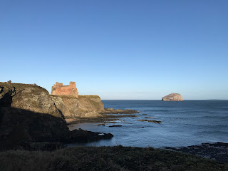 A photo of a view of Tantallon Castle and the cliffs beneath it, with the Bass Rock in the sea in the background, taken from the path to Oxroad Bay.  Photo by Kevin Nosferatu for the Skulferatu Project.