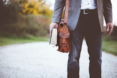 Persoană care ține o geantă pe umăr și o Biblie - foto de Ben White - unsplash.com