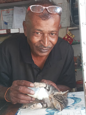 Mr Binesh.Kumar  feeding a orphaned cat.