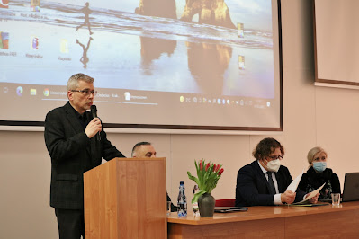 profesor Piotr Zwierzchowski przemawiający do publiczności, przy stole plenarnym prelegenci.