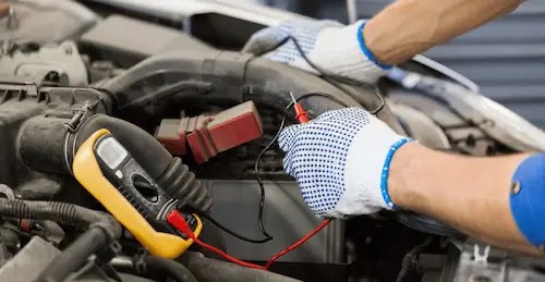 Mechanic tests battery with multimeter