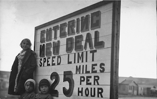 Woman and 2 childrenin fron of roadside sign "Entering New Deal Speed limit 25 mph", Montana, for LIFE magazine in 1936