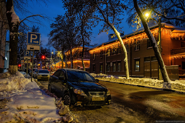 Улица в новогодней подсветке на деревянных зданиях