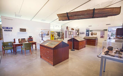 Inside of Hawkesbury Regional Museum, including display cabinets, a table with chairs, and displays on the walls