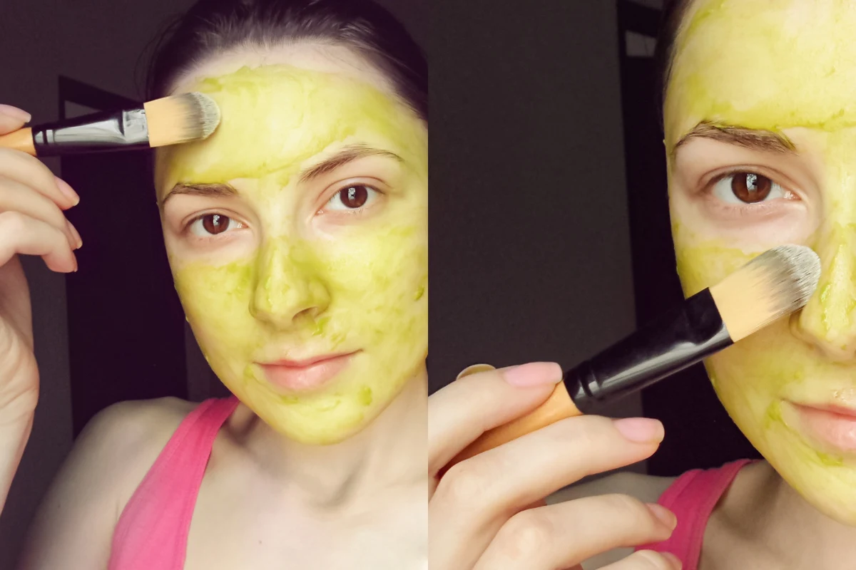 woman applying avocado mask to her face with a synthetic brush