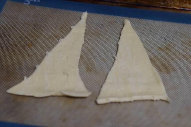 Two crescent roll triangles on a baking sheet.