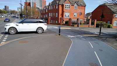 A SUV leaving a side road with a cycle track behind it.